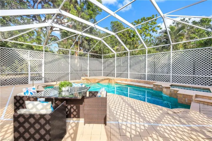View of swimming pool with an in ground hot tub, a patio, and glass enclosure