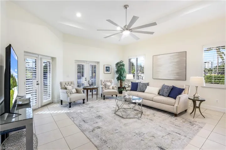 Tiled living room with french doors, a tray ceiling, plenty of natural light, and ceiling fan.