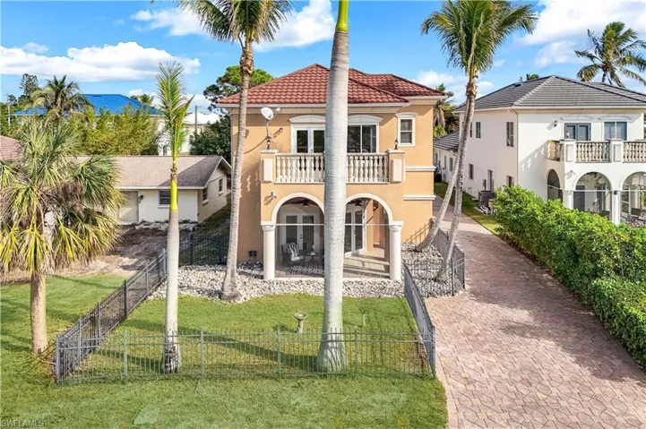 Front view of the house with fenced in yard, balcony and driveway.