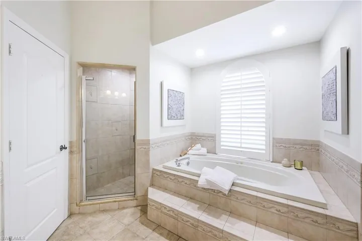 Primary bathroom with walk-in shower jacuzzi tub and ceramic tile flooring.
