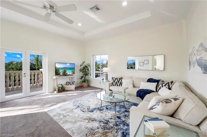 Second-floor living room with a beautiful view, french doors and ceiling fan.