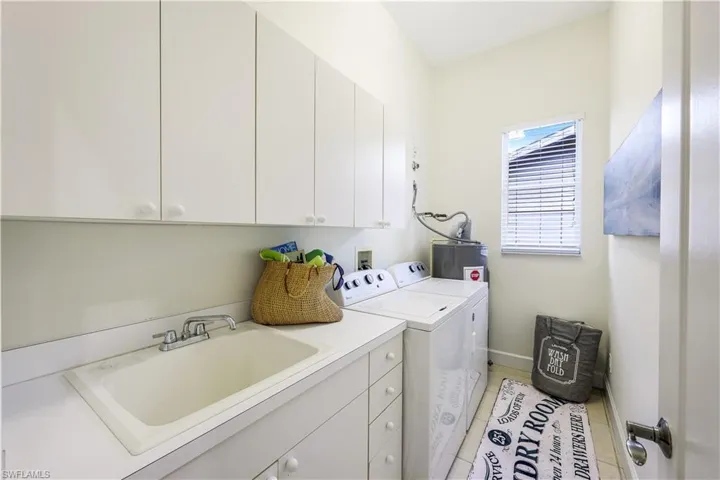 Laundry room with a laundry sink and an abundance of cabinets for storage.