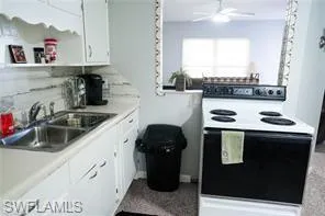 Kitchen with white cabinetry, sink, ceiling fan, white range with electric cooktop, and decorative backsplash