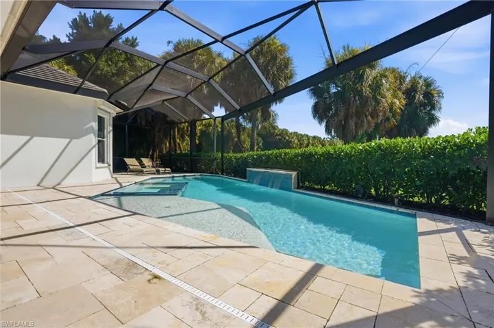 an inground pool with a built-in spa, and a stone-clad waterfall feature
