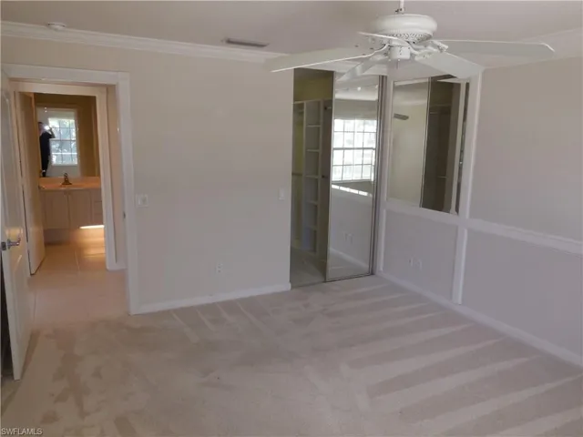 Spare room with ceiling fan, ornamental molding, and light carpet