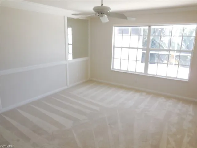 Spare room with light colored carpet, crown molding, and a ceiling fan