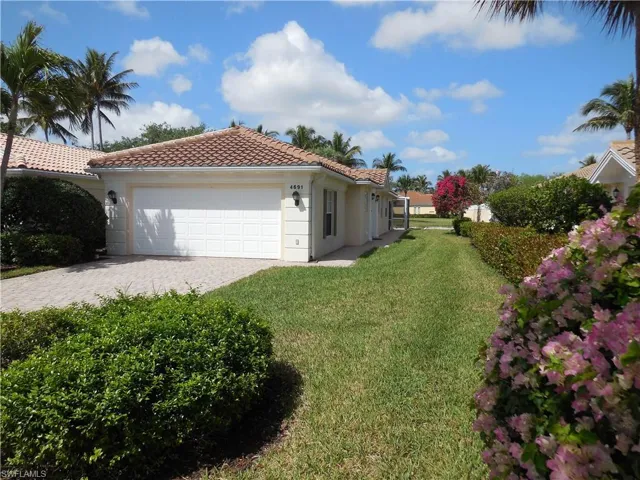 View of property exterior with a yard, a garage, a tiled roof, decorative driveway, and stucco siding