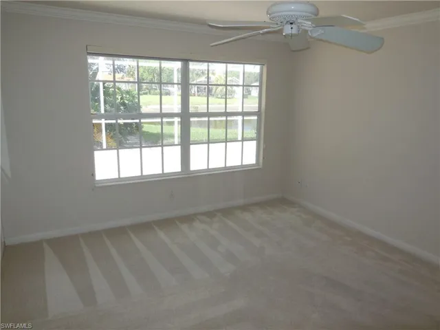 Empty room featuring ornamental molding, light colored carpet, and a ceiling fan
