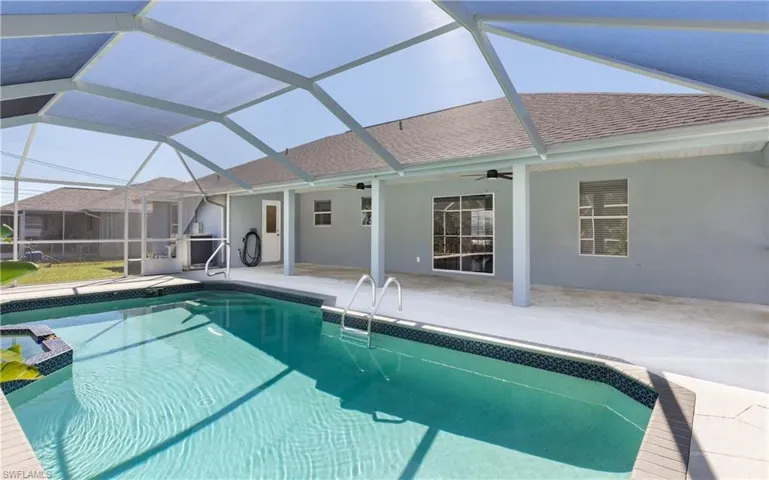 View of swimming pool featuring glass enclosure, a patio, a ceiling fan, and a pool with connected hot tub