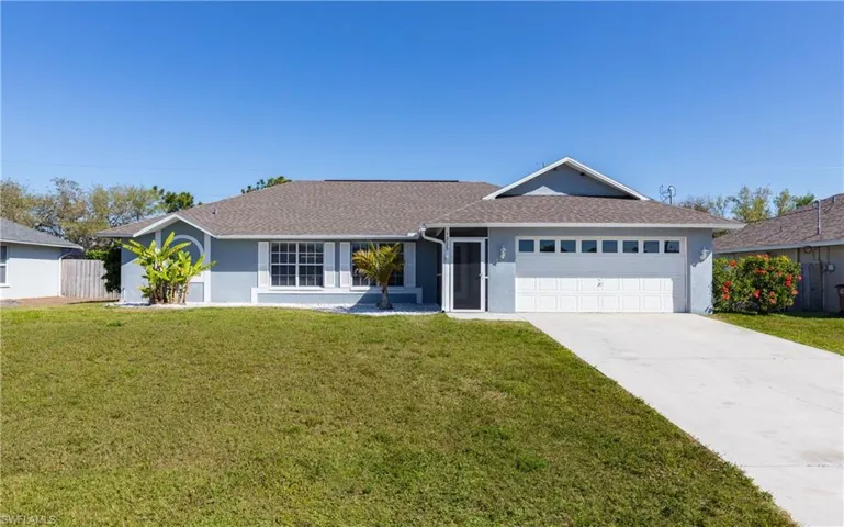 Ranch-style house with a garage, stucco siding, concrete driveway, and a front lawn