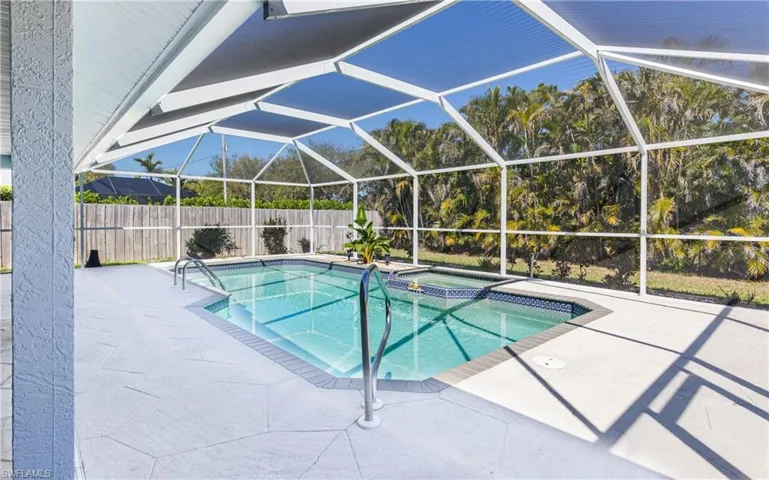 View of swimming pool featuring a patio, fence, a pool with connected hot tub, and a lanai