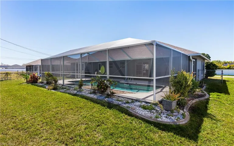 Back of property with a lanai, a yard, fence, and a fenced in pool