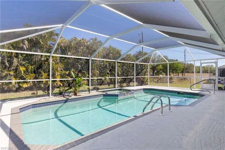 View of swimming pool with a patio, a pool with connected hot tub, and a lanai