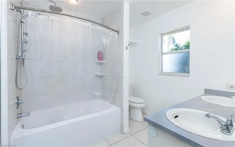 Bathroom featuring tile patterned floors, visible vents, shower / bath combo, and a sink