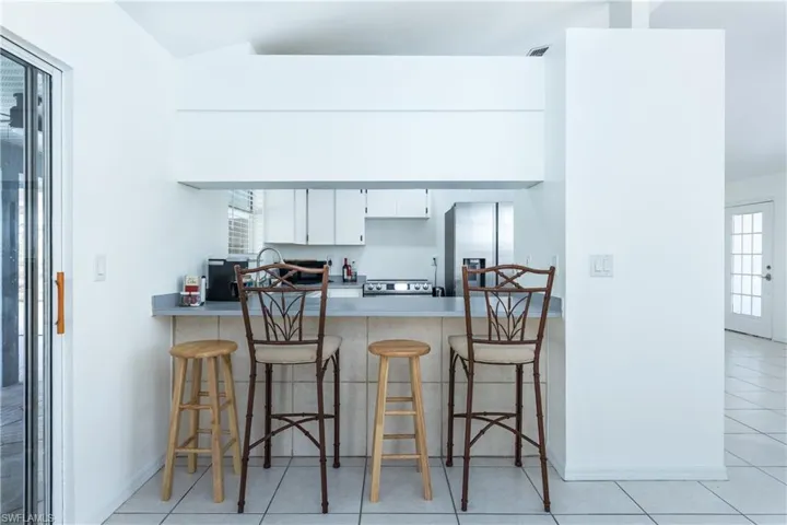 Kitchen with baseboards, a breakfast bar, a peninsula, light countertops, and appliances with stainless steel finishes