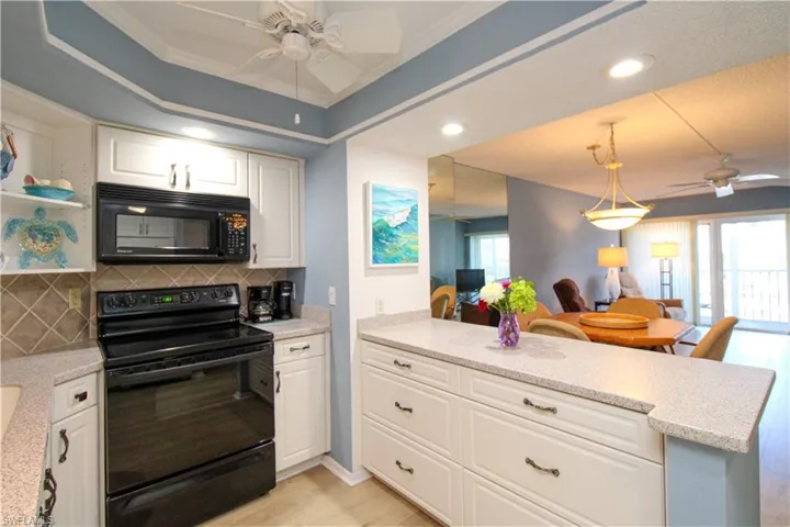 Kitchen featuring decorative backsplash, open floor plan, white cabinets, a peninsula, and black appliances