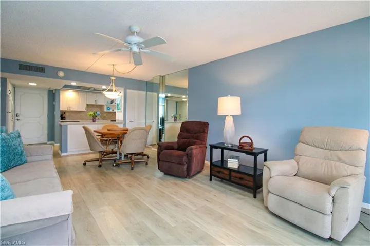 Living area featuring light wood finished floors, a ceiling fan, visible vents, and a textured ceiling