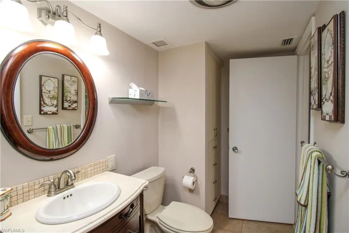 Bathroom featuring tasteful backsplash, visible vents, toilet, tile patterned flooring, and vanity
