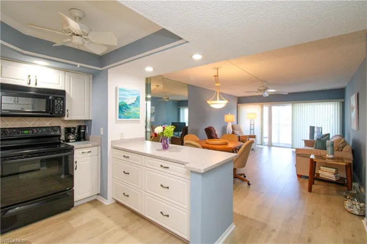 Kitchen with tasteful backsplash, light wood-style flooring, open floor plan, a peninsula, and black appliances