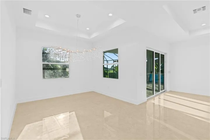 Spare room with a raised ceiling, recessed lighting, and a chandelier
