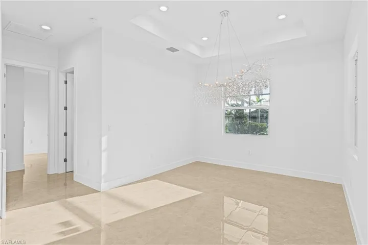 Empty room featuring a raised ceiling, recessed lighting, and light tile patterned floors