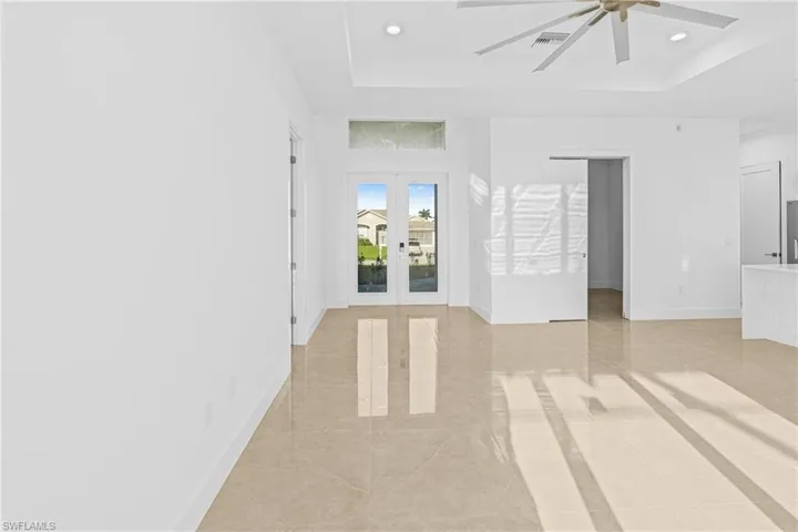 Spare room with a tray ceiling, french doors, light tile patterned flooring, ceiling fan, and recessed lighting
