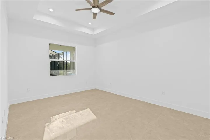 Empty room featuring a raised ceiling, recessed lighting, and a ceiling fan