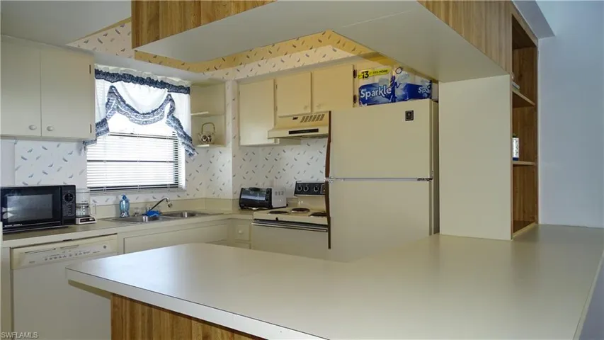 Kitchen featuring a peninsula countertop, white appliances, and ample cabinetry