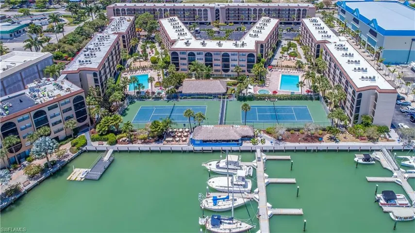 Waterfront condominium complex featuring a private marina with multiple boat slips, two outdoor swimming pools, and two tennis courts