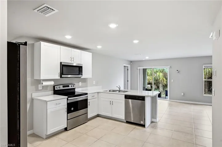 Kitchen featuring stainless steel appliances, white cabinetry, a peninsula, recessed lighting, and light tile patterned floors