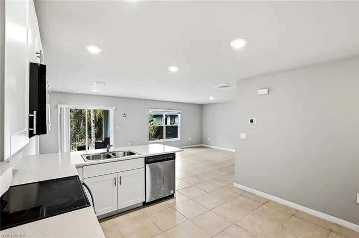 Kitchen with range with electric cooktop, stainless steel dishwasher, white cabinetry, a peninsula, and black microwave