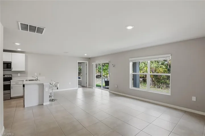 Kitchen featuring light countertops, open floor plan, stainless steel appliances, white cabinetry, and healthy amount of natural light
