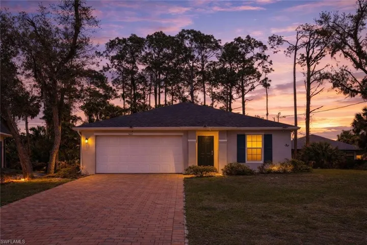 Ranch-style house with stucco siding, an attached garage, a front lawn, and decorative driveway