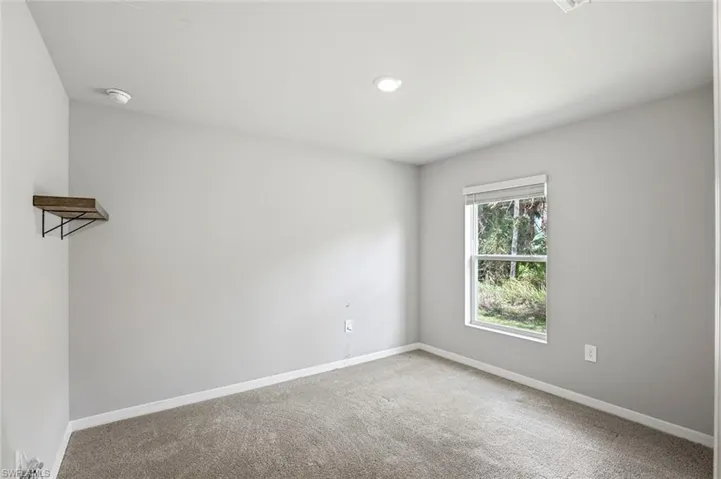 Empty room featuring baseboards and light carpet