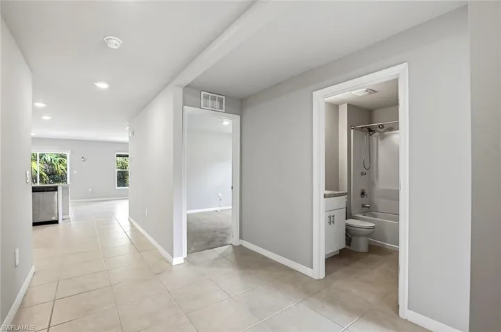 Hallway with light tile patterned floors and recessed lighting