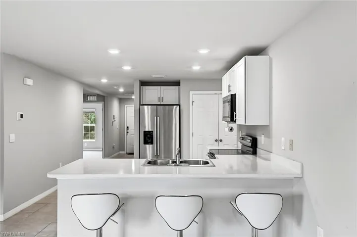 Kitchen featuring stainless steel fridge, a peninsula, electric range, a breakfast bar area, and recessed lighting