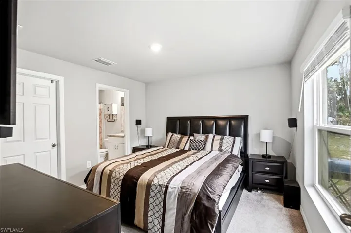 Bedroom featuring light colored carpet and ensuite bathroom