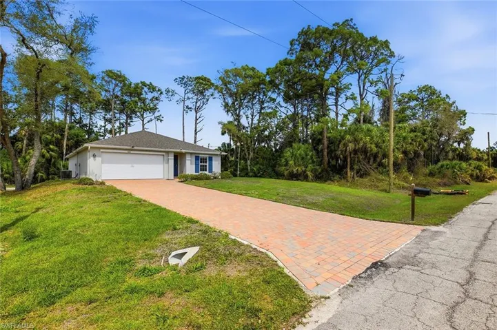 View of front of property featuring a front lawn, decorative driveway, an attached garage, and stucco siding