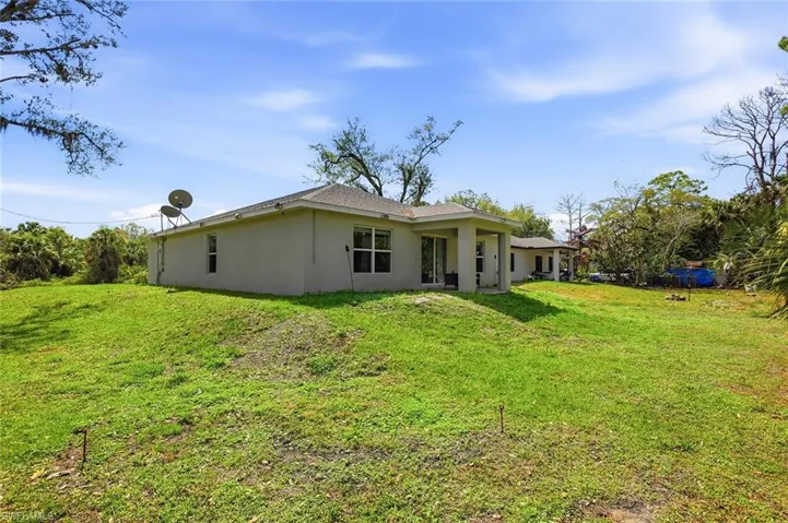 Rear view of property featuring stucco siding and a yard