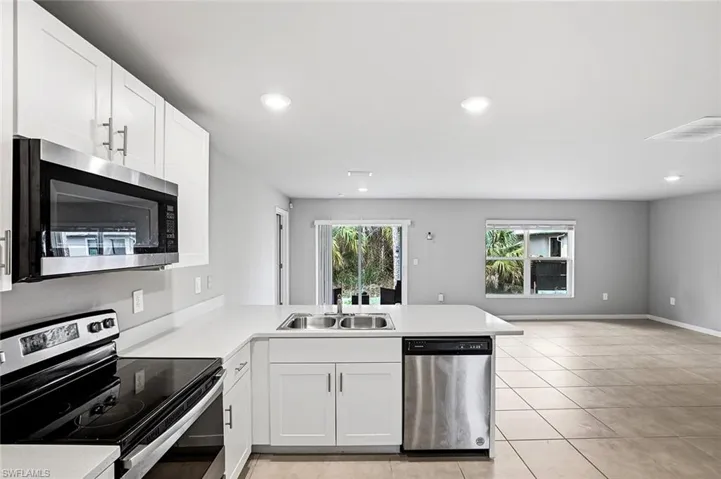 Kitchen featuring stainless steel appliances, light countertops, a peninsula, white cabinetry, and recessed lighting
