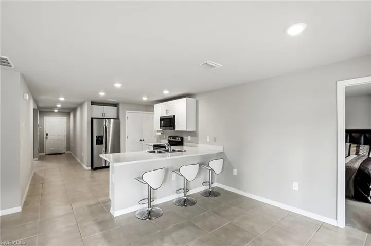 Kitchen featuring recessed lighting, light countertops, a breakfast bar area, stainless steel appliances, and a peninsula