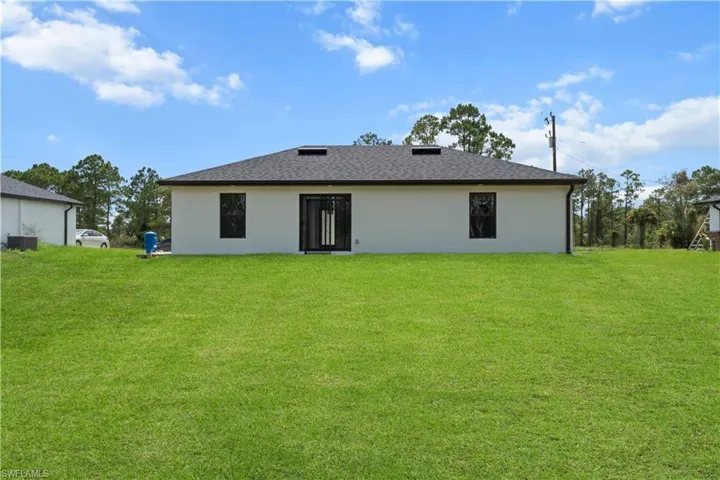 Rear view of house with a lawn and roof with shingles