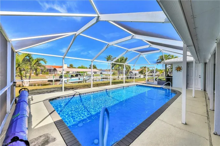 View of swimming pool featuring a patio and glass enclosure