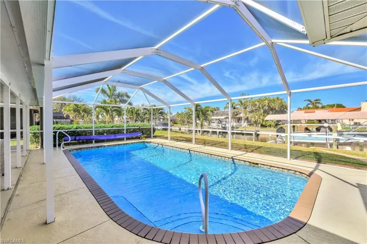 View of pool with a patio area and glass enclosure