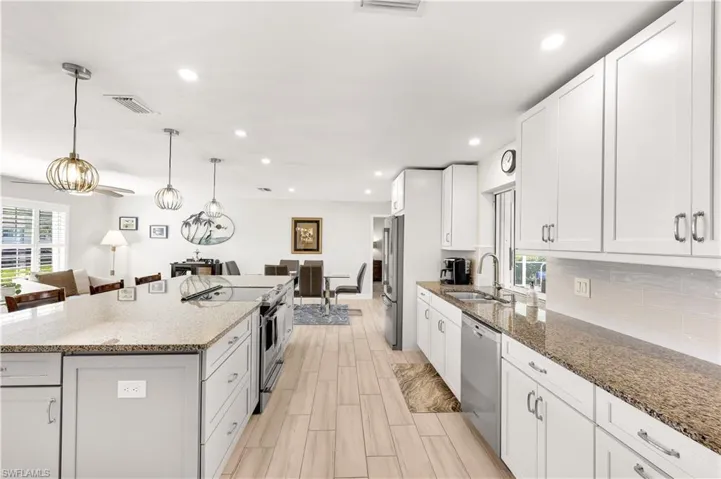Kitchen with stainless steel appliances, white cabinetry, and a kitchen island