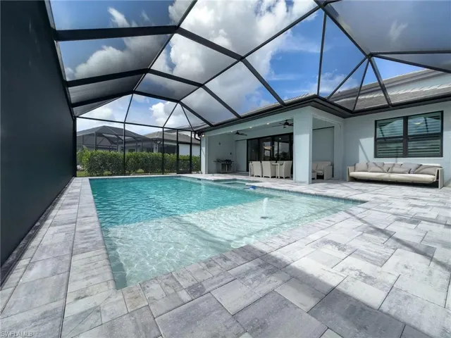 Screened pool enclosure with a rectangular swimming pool, integrated spa, and fountain feature