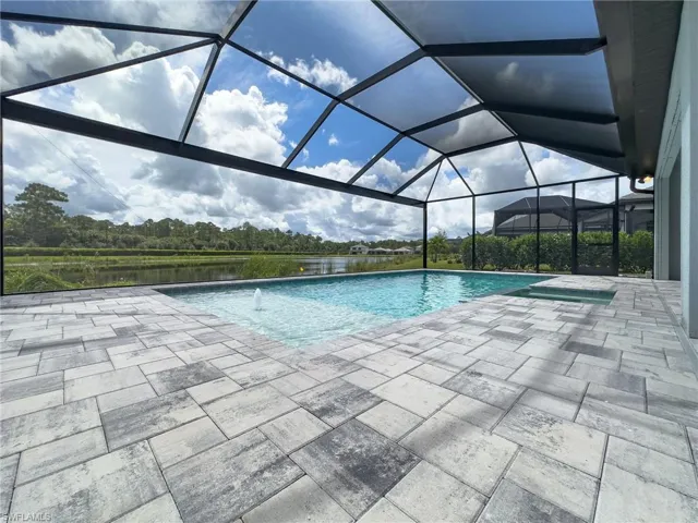 Screened outdoor living area featuring a rectangular pool with an integrated spa, a paver patio, and a water feature