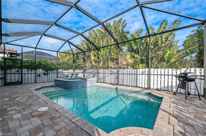 View of swimming pool with grilling area, a patio area, a fenced backyard, a pool with connected hot tub, and a lanai