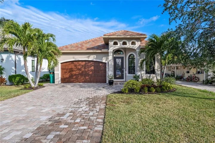 Mediterranean / spanish house featuring stucco siding, a garage, decorative driveway, a front yard, and a tile roof