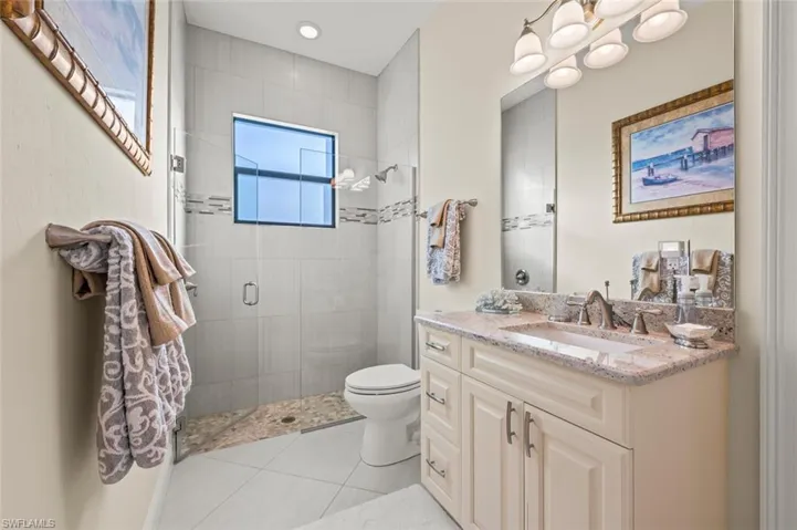 Bathroom featuring a shower stall, vanity, tile patterned floors, and a chandelier
